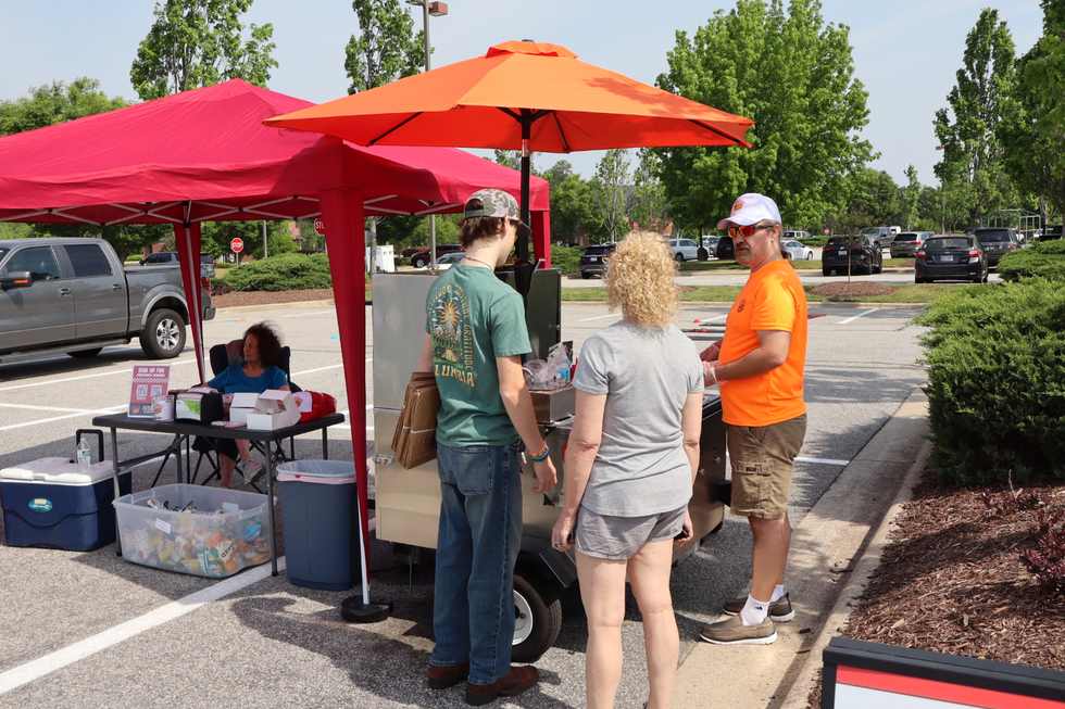 Guests smiling with Cheesedogs food at an outdoor event