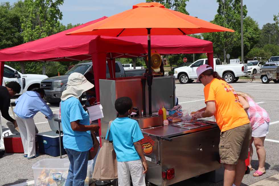 Cheesedogs cart preparing a hot dog with unique toppings